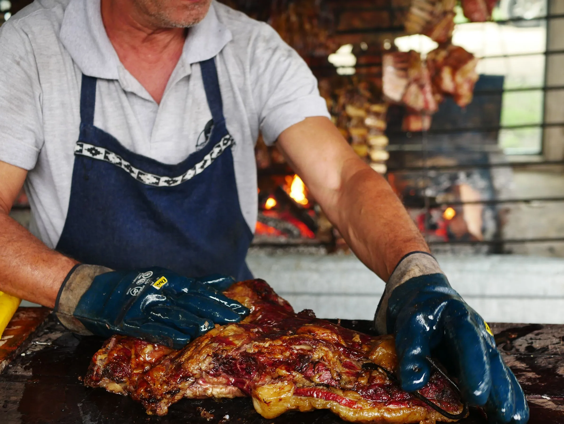El parrillero de Asador Artebe trabajando una pieza de carne junto al fuego
